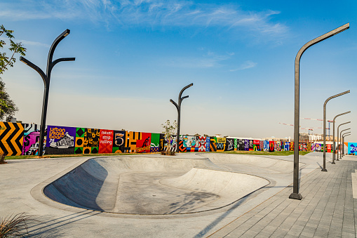 Newly made skate park with modern look steel light poles. Colorful boundary wall and precast concrete pavers. Empty.