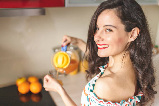 istock Woman preparing orange and carrot juice 1215546440