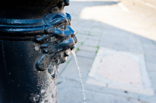 Man drinking water from broken water pipe in the streets of Delhi