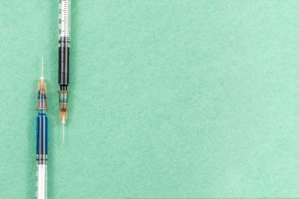 A syringe with an injection solution on green background stock photo
