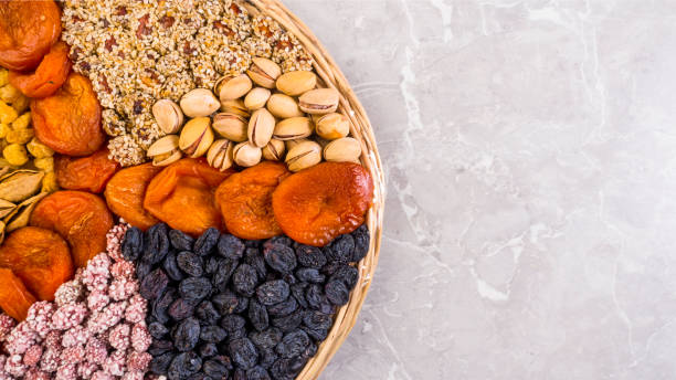 placa de madera con un conjunto de nueces, albaricoques, pasas, sésamo - peanut bowl nut circle fotografías e imágenes de stock