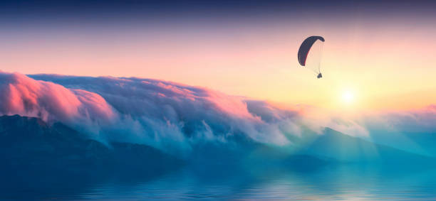 silhueta de parapente em uma luz do nascer do sol acima da ilha - aerofoil - fotografias e filmes do acervo