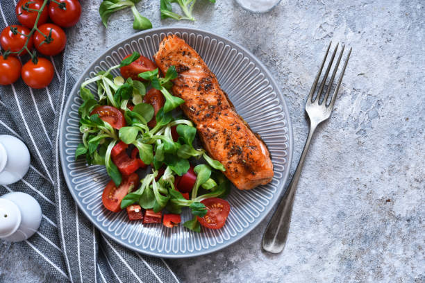 istock Grilled salmon slice and salad with tomatoes on the kitchen table. Menu for the restaurant. 1215552679