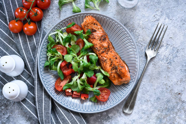 istock Grilled salmon slice and salad with tomatoes on the kitchen table. Menu for the restaurant. 1215552689