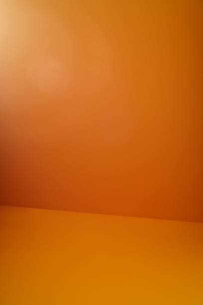 istock Orange colored wall and floor with a soft light leak from upper left corner 1215552790