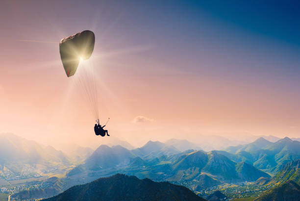 Paraglide silhouette over mountain peaks Paraglide silhouette over mountain peaks. airfoil photos stock pictures, royalty-free photos & images