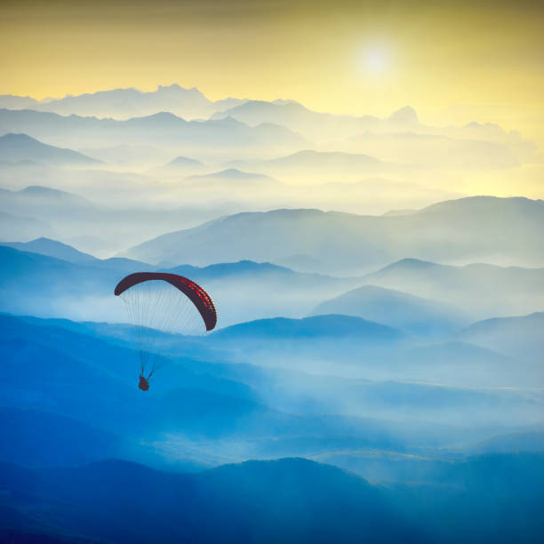 Paraglide silhouette in a light of sunrise Paraglide silhouette in a light of sunrise above the misty Crimea valley. airfoil photos stock pictures, royalty-free photos & images
