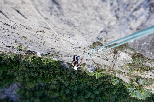 Young man is climbing in Potrero de Chico in Mexico, view down on his climbing partner