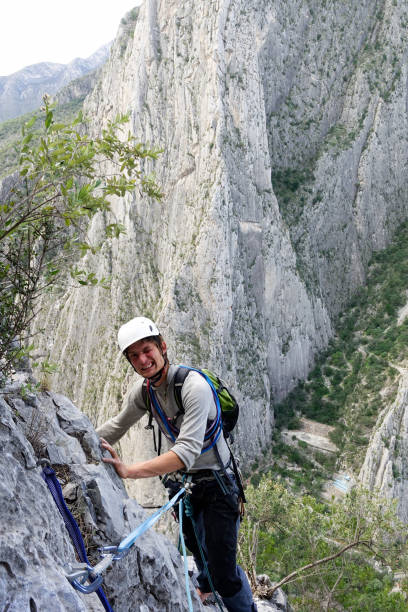 młody człowiek wspina się w potrero de chico w meksyku i patrząc w górę w aparacie, jest naprawdę szczęśliwy, uśmiechnięty i rock ridge jest za nim - mountain climbing rock climbing motivation awe zdjęcia i obrazy z banku zdjęć