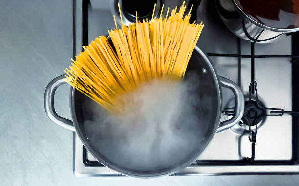 cottura di spaghetti crudi nell'acqua bollente contenuta in una casseruola - italian culture ingredient spaghetti food foto e immagini stock