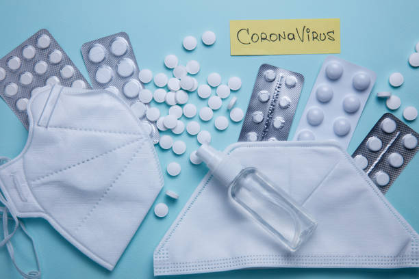 istock Coronavirus phrase text on a blue background with pills, sanitizer and protective masks 1215560325