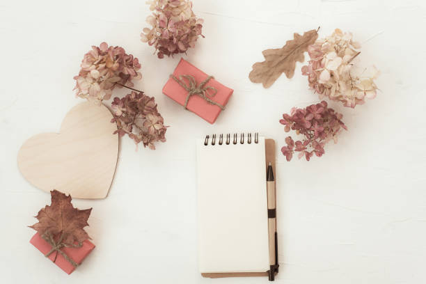 istock Workspace with notebook on white background. Autumn composition with dry flowers and leaves. Flat lay, top view. 1215560496