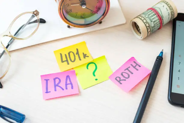 Photo of 401k ira roth on pieces of colorful paper dollars on table. Pension concept. Retirement plans.