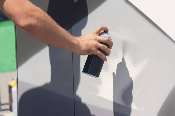 Close up with young boy doing graffiti, holding spray can with hand. Spray aerosol paint for graffiti. Street artist paints graffiti on the wall