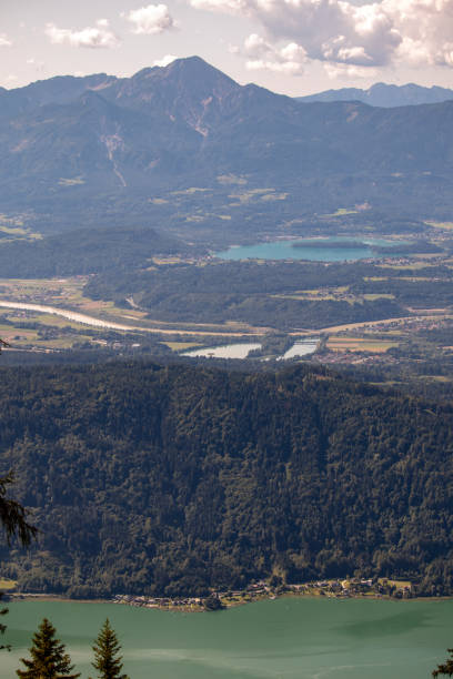 panorama der österreichischen alpen am ossiacher see mit den bergen der karawanken mit gleitschirmen - paragliding sport austria parachuting stock-fotos und bilder