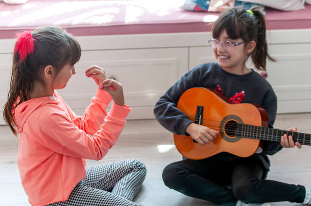 istock Cute girl playing guitar with her viewer 1215569372