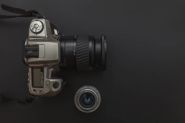 istock Photographer workplace with dslr camera system and lens on dark black table background. Hobby travel photography concept. Flat lay top view copy space 1215569741