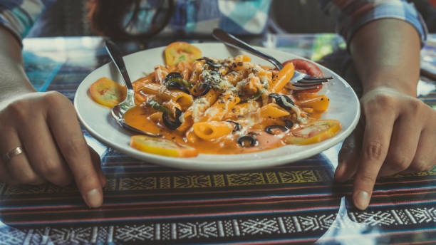 istock Delicious pasta with tomato sauce. Silverware placed on plate of palatable pasta with tomato sauce and olives on ornamental table in cafeteria 1215569906