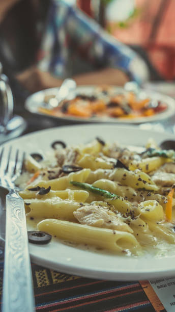 Yummy pasta on cafe table. Closeup plate with portion of tasty pasta with cream sauce placed on table in restaurant
