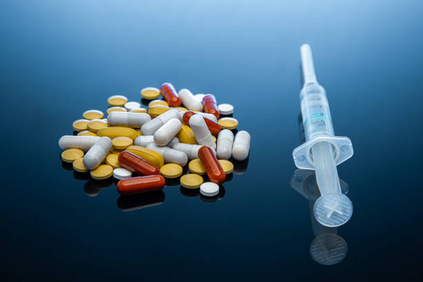 istock Syringe and pills on dark blue surface stock photo 1215571433