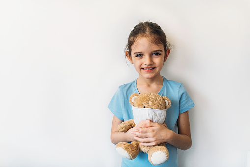 Cute girl holding teddy bear in medical masks. Coronavirus epidemic