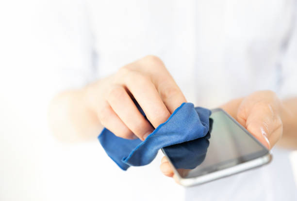 A person cleaning mobile phone to prevent the spread of germs, bacteria and coronavirus stock photo