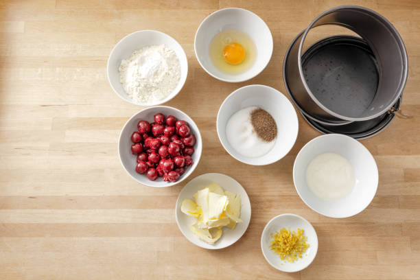 istock Ingredients in white bowls to bake a cherry cake in a springform pan on a wooden kitchen countertop, copy space, high angle view from above 1215575769