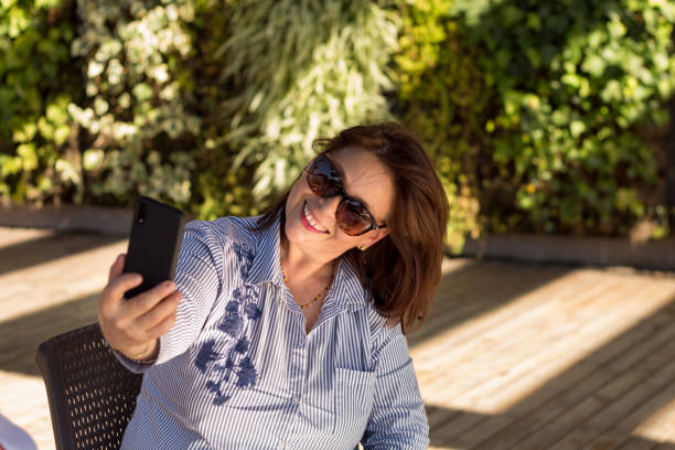 istock A woman sitting outdoors relax and taking a selfie 1215576065