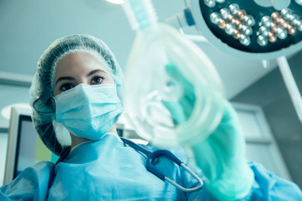 Experienced anesthesiologist doing her work stock photo Woman in medical uniform standing with a mask for narcosis in her hand surgical needle stock pictures, royalty-free photos & images