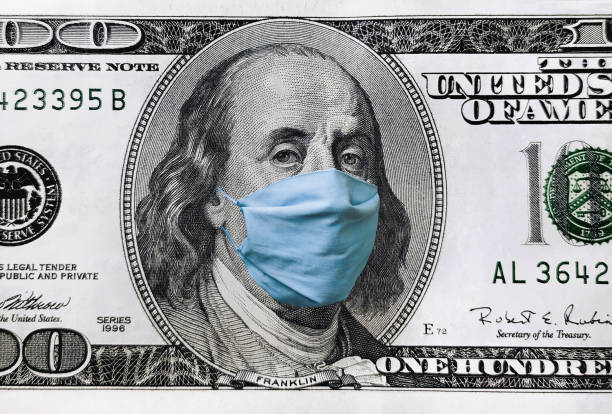 Blue medical mask on the face of Benjamin Franklin with a hundred dollar bill. The concept of the global economic crisis associated with the coronavirus quarantine COVID-19. stock photo