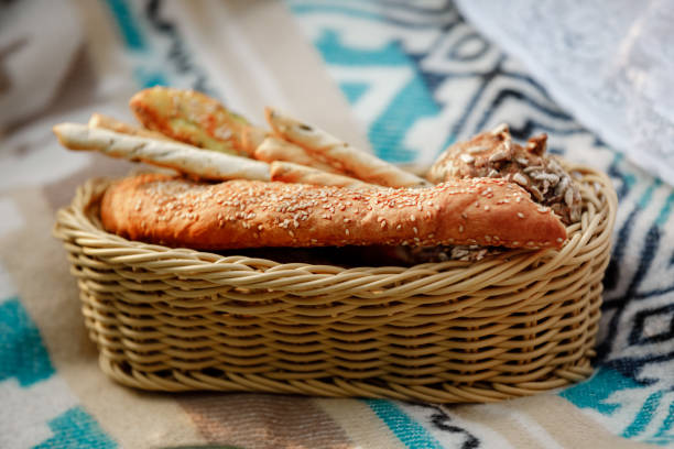 Wicker basket with bread. Bread, buns and grissini inside basket. Fresh bakery products on picnic. selective focus.