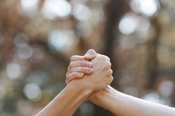 istock two people shaking hands isolated on a natural background in the park. isolate two hands holding on another, signal of collaboration. copy space. selective focus 1215579306