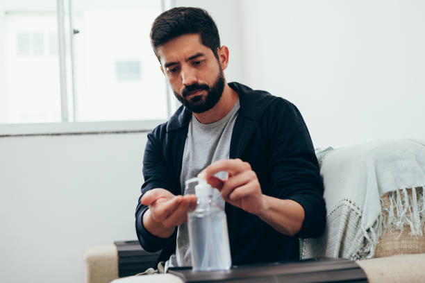 istock Coronavirus, covid-19 and quarantine concept. Man in quarantine sanitizing his hands with alcohol gel 1215583545