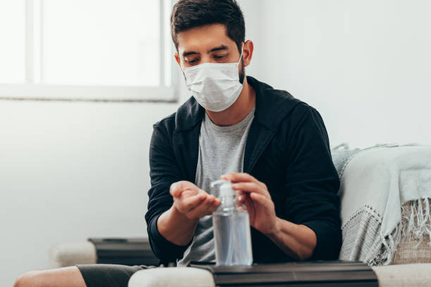 istock Coronavirus. Man in quarantine wearing protective mask sanitizing his hands with alcohol gel 1215583554