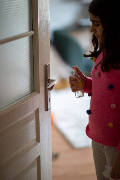 istock Little girl sanitizing door handle with antibacterial spray 1215585975