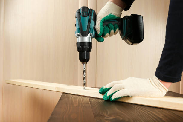 worker's hand is drilling wood plank by cordless drill