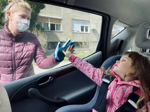 Photo of Granddaughter and granny saying hi over the car window due to COVID-19 social distancing protective measures