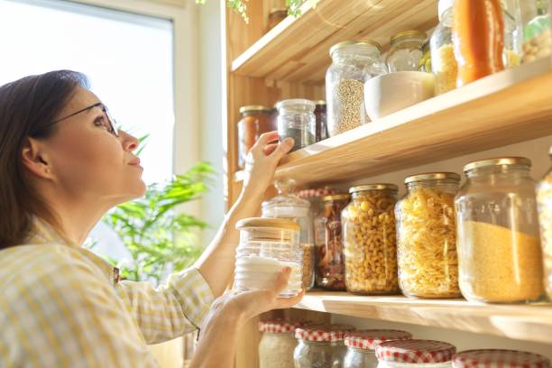 パントリーの食品貯蔵、手に砂糖の瓶を持つ女性。 - bean legume lentil vegan food ストックフォトと画像