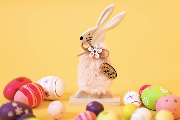 istock Wooden Easter Bunny with Easter eggs, on an isolated yellow background 1215597291