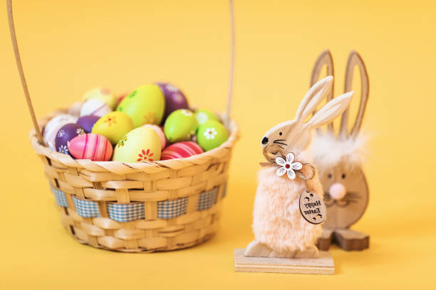 istock Wooden Easter Bunny with Easter eggs, on an isolated yellow background 1215597824