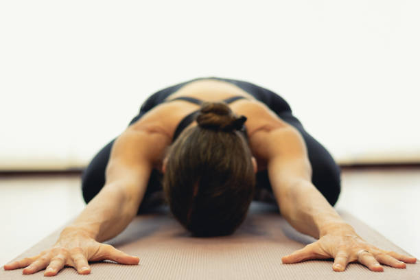 yogui mujer practica pose infantil en estudio brillante - child yoga gym women fotografías e imágenes de stock