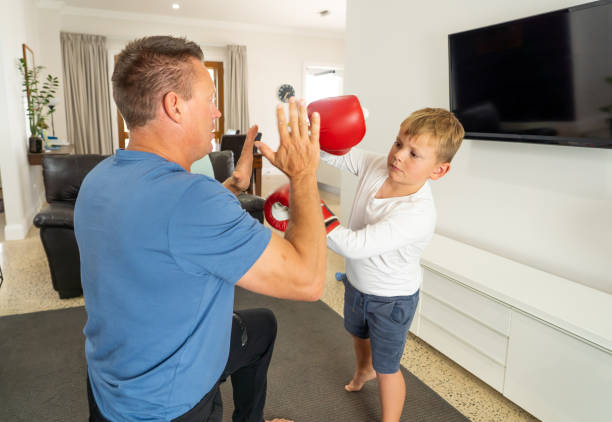 istock COVID-19 Shutdown. Father and son having fun boxing together and staying physically active at home during coronavirus quarantine. Stay home, Exercise, Health Self-care for Coronavirus isolation. 1215600118