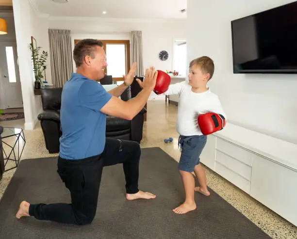 COVID-19 Shutdown. Father and son having fun boxing together and staying physically active at home during coronavirus quarantine. Stay home, Exercise, Health Self-care for Coronavirus isolation.
