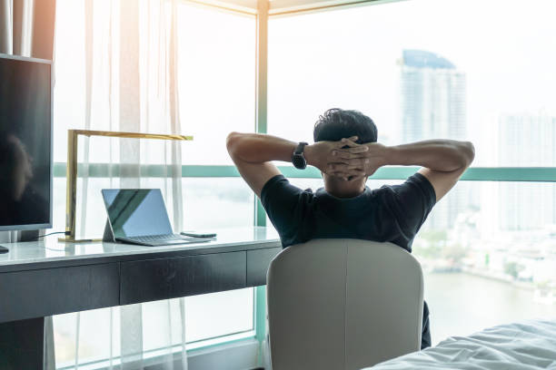 Life-work balance and city living life style concept of business man relaxing, take it easy in office room resting with thoughtful mind thinking of lifestyle quality looking forward to cityscape equilibrio de trabajo de vida y concepto de estilo de vida de vida de la ciudad de hombre de negocios relajante, tómelo con calma en la sala de oficina descansando con pensamiento reflexivo de la calidad del estilo de vida con ganas de paisaje urbano