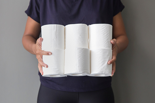 Close up shot of Asian woman holding stacks of toilet paper