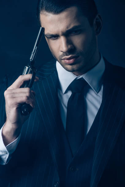 istock Front view of thoughtful gangster with gun on dark blue background 1215603088