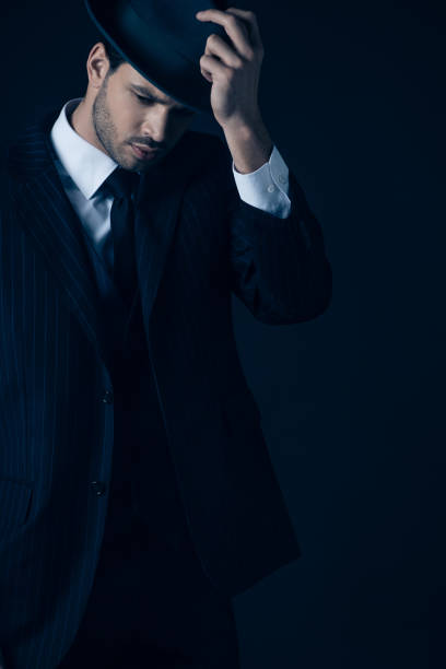 istock Thoughtful mafioso holding felt hat on dark blue 1215603098