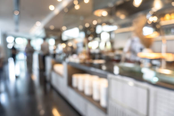 istock Buffet at hotel restaurant interior blur background with blurry open kitchen counter bar of food catering service business with chef staff cooking for breakfast, lunch or dinner meal 1215603373
