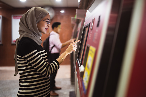 Young woman using ATM to check funds.