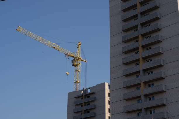 From below of constructing building with high crane under clear sky